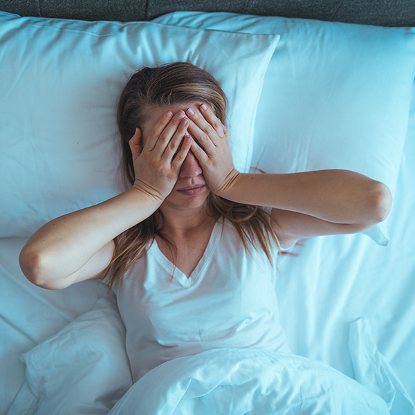 Stressed woman lying on bed late at night suffering from sleep apnea