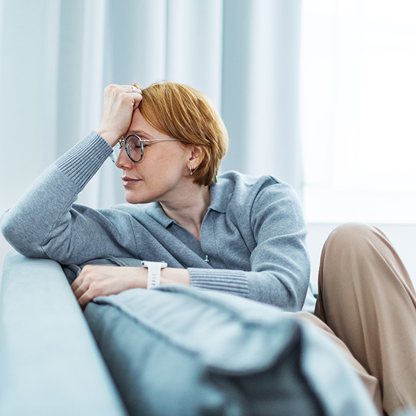 Mid adult woman sitting on safe at home with headache